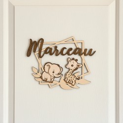 Plaque prénom personnalisée en bois savane avec éléphant et girafe accrochée sur une porte de chambre d’enfant