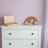Pancarte licorne arc-en-ciel et boîte de rangement en bois ouverte, posées sur une commode de chambre d’enfant.