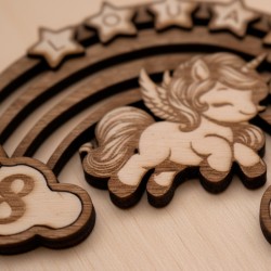 Gros plan sur la gravure au laser de la licorne et des arcs colorés en bois de la pancarte.