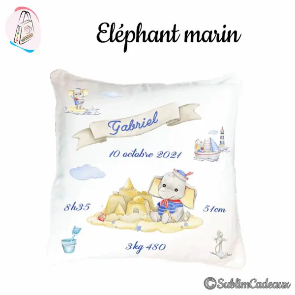 Coussin de naissance blanc imprimé d'un éléphanteau matelot devant un château de sable, avec bannière, phare et bateau