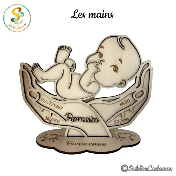 Décoration de naissance en bois découpé au laser, bébé tenu dans deux mains, gravée des informations de naissance et du mot Bienvenue