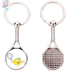 Porte-clés en forme de raquette de tennis en métal, face illustrée d'une balle jaune souriante, dos figurant le cordage