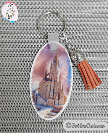 Porte-clés ovale château enneigé avec pompon en suédine caramel, image à personnaliser