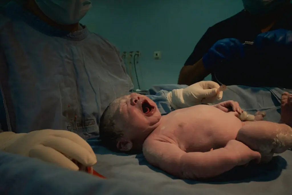 Nouveau-né qui pleure juste après sa naissance, entouré du personnel médical en salle d'accouchement